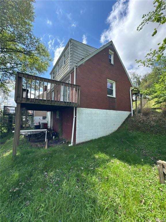 view of side of property featuring brick siding, a deck, and a yard