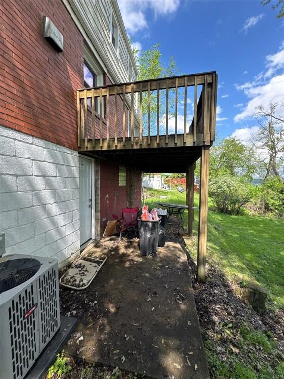 rear view of property with cooling unit, a lawn, a wooden deck, and a patio area