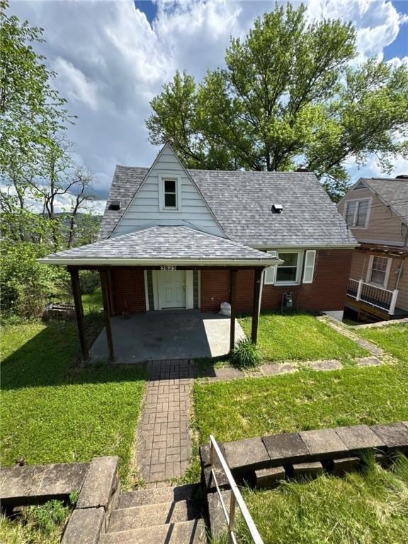 rear view of house featuring a yard and roof with shingles