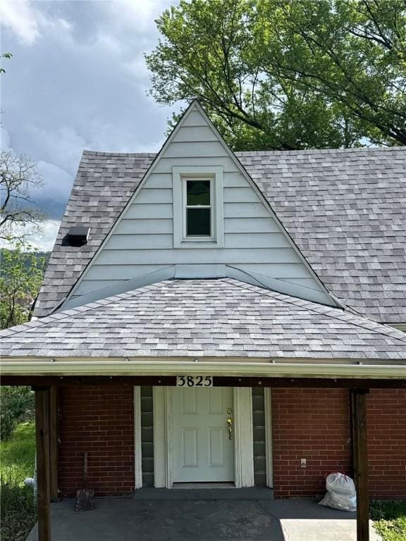 view of front of house featuring roof with shingles and brick siding