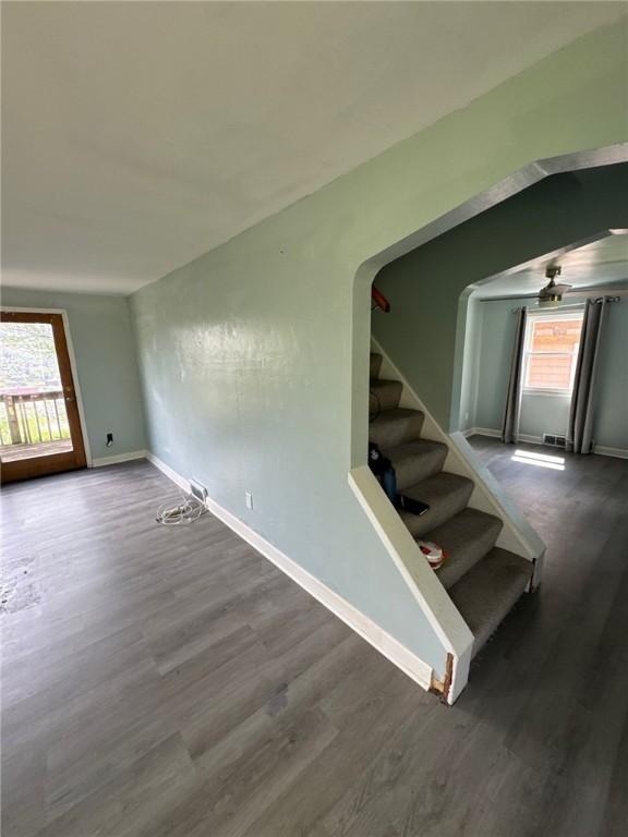 stairs featuring healthy amount of natural light, wood finished floors, baseboards, and a ceiling fan