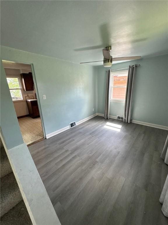 empty room with wood finished floors, a ceiling fan, and baseboards