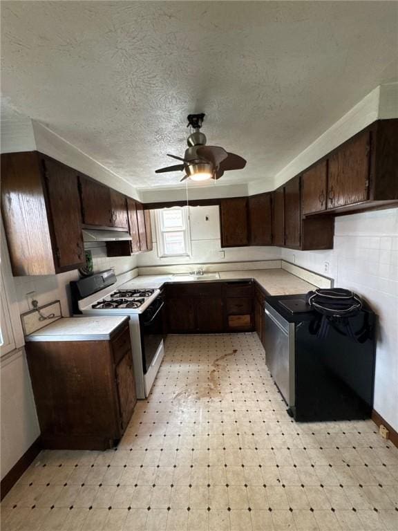 kitchen featuring white gas stove, ceiling fan, range, light flooring, and a textured ceiling