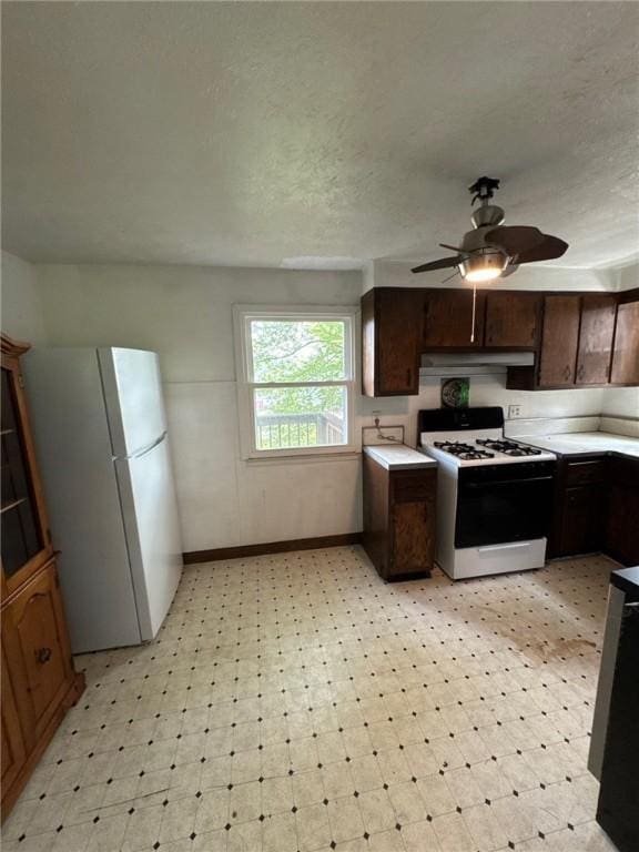 kitchen featuring white appliances, light floors, a ceiling fan, light countertops, and a textured ceiling