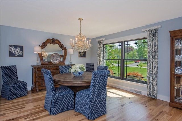 dining space with a chandelier, light wood-type flooring, and baseboards