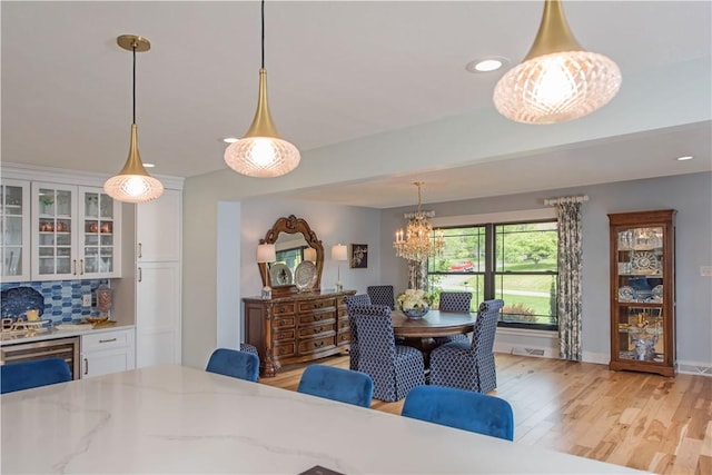 dining space featuring a chandelier, light wood finished floors, recessed lighting, and baseboards