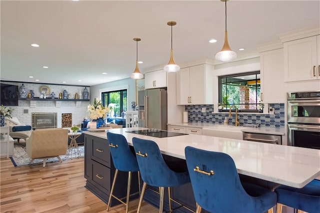 kitchen featuring stainless steel appliances, a sink, backsplash, white cabinets, and recessed lighting