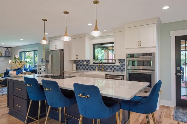 kitchen with stainless steel appliances, a sink, decorative backsplash, white cabinets, and recessed lighting