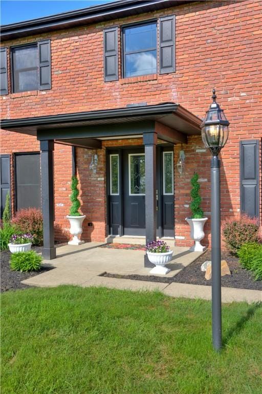 property entrance with brick siding and a yard