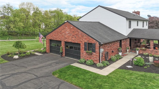 view of front of home with brick siding, a front yard, a shingled roof, and driveway