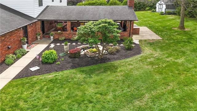 view of green lawn with a patio area, a storage unit, and an outbuilding