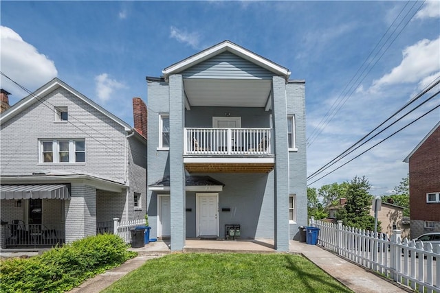 back of house featuring a balcony, brick siding, and a patio
