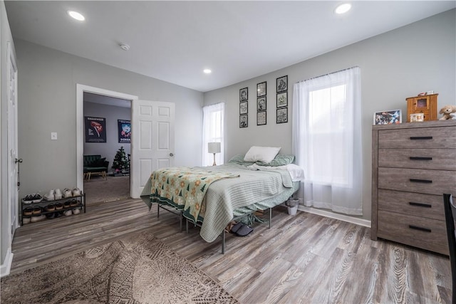 bedroom featuring multiple windows, wood finished floors, recessed lighting, and baseboards
