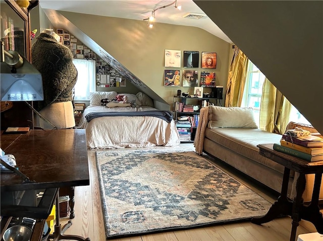 bedroom featuring hardwood / wood-style floors, rail lighting, and lofted ceiling