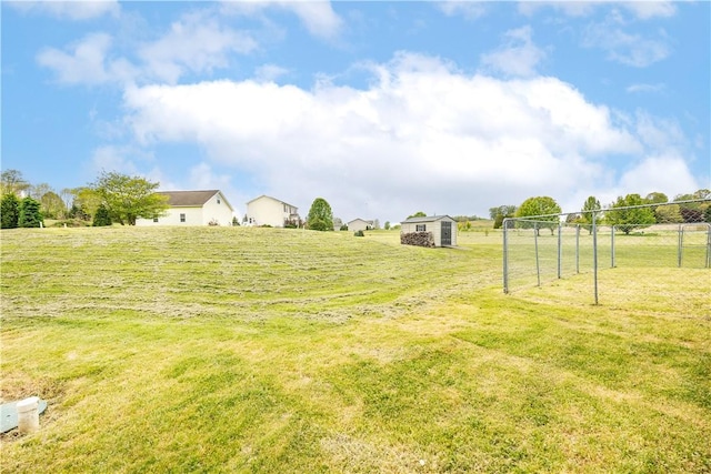view of green lawn with an outdoor structure, a rural view, and a storage shed