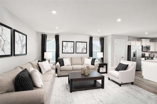 living area with light wood-style flooring, healthy amount of natural light, and recessed lighting