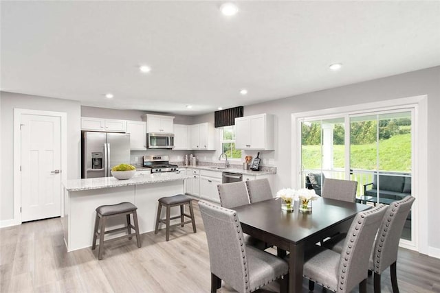 dining room with light wood finished floors, recessed lighting, and baseboards