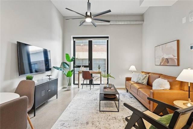 living area with concrete flooring, a ceiling fan, and baseboards