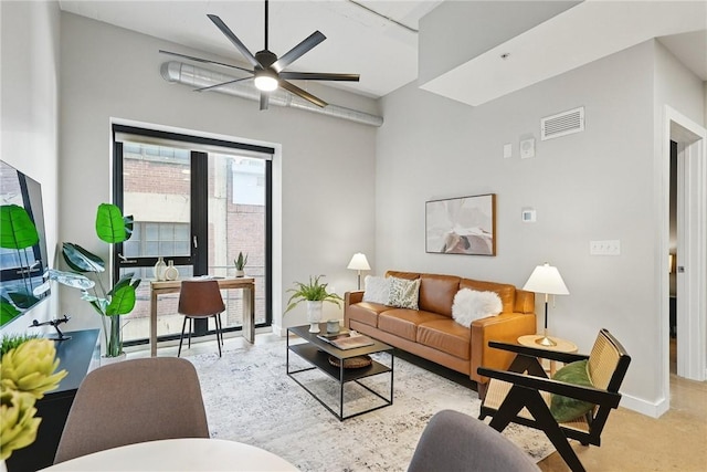 carpeted living area with ceiling fan and baseboards