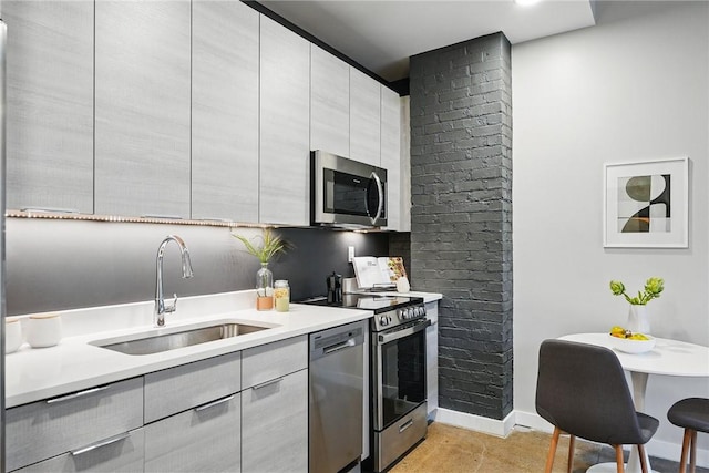 kitchen featuring stainless steel appliances, a sink, light countertops, modern cabinets, and baseboards