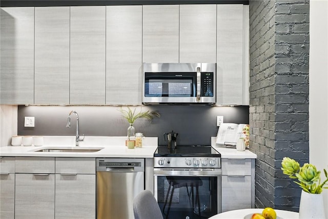kitchen with appliances with stainless steel finishes, a sink, modern cabinets, and light countertops