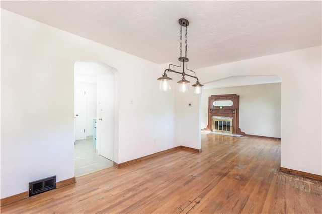 5251 Meadowgreen Dr, Whitehall, PA 15236 - unfurnished dining area with arched walkways, light wood finished floors, baseboards, and a glass covered fireplace