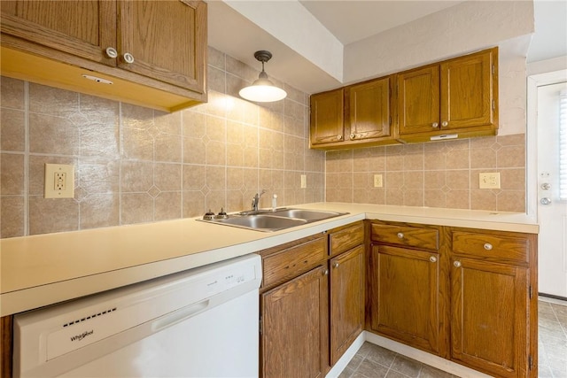 kitchen with white dishwasher, a sink, brown cabinets, backsplash, and light countertops