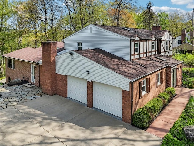 view of property exterior featuring a chimney, brick siding, and driveway