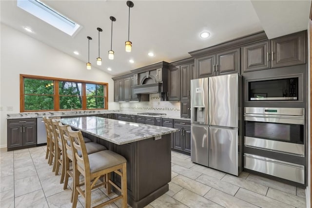 kitchen with stainless steel appliances, a warming drawer, a skylight, light stone counters, and a breakfast bar