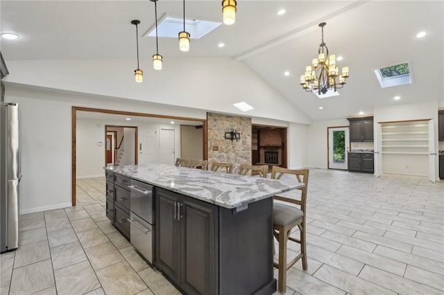 kitchen with a skylight, open floor plan, stainless steel appliances, a kitchen bar, and high vaulted ceiling