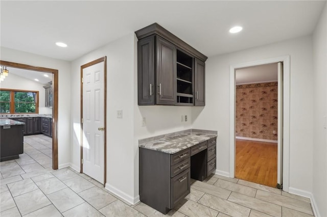 kitchen with light stone countertops, open shelves, baseboards, recessed lighting, and dark brown cabinets