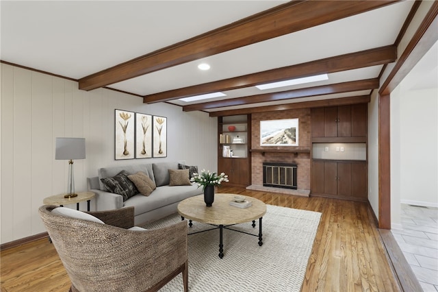 living room with beamed ceiling, light wood-style flooring, a fireplace, and baseboards