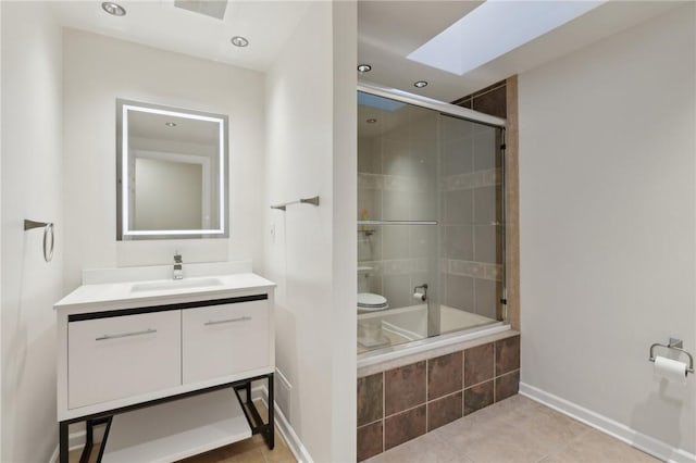 bathroom with a skylight, a tile shower, toilet, vanity, and recessed lighting