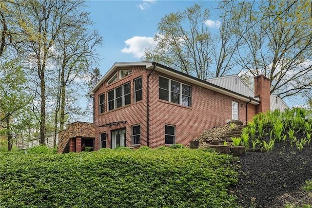 view of property exterior featuring brick siding and a chimney