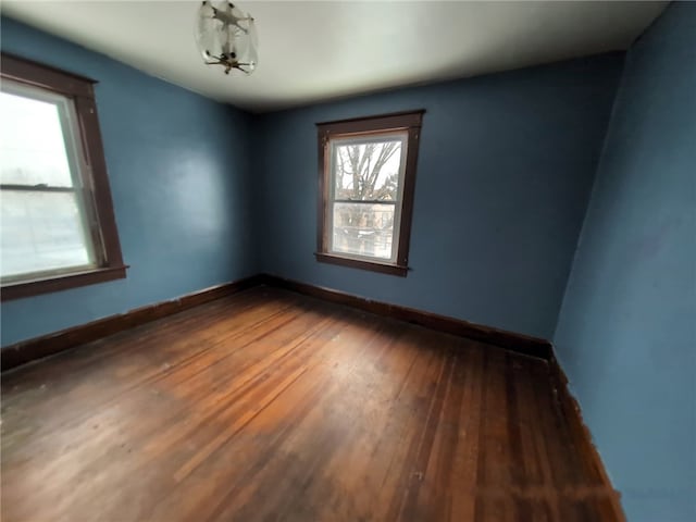unfurnished room with wood-type flooring and baseboards
