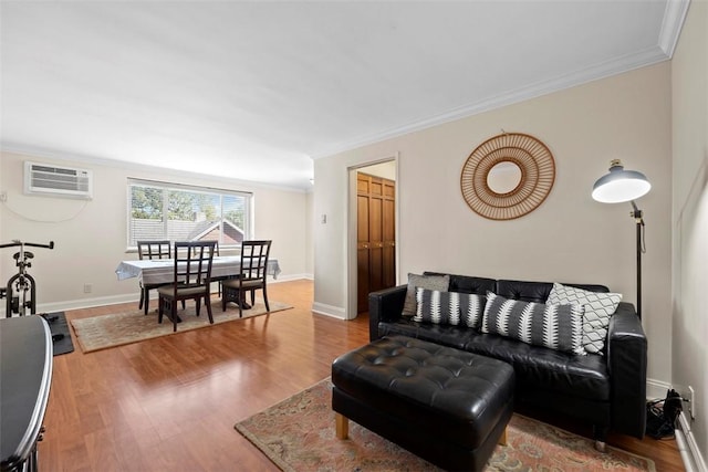 living room with an AC wall unit, crown molding, wood finished floors, and baseboards
