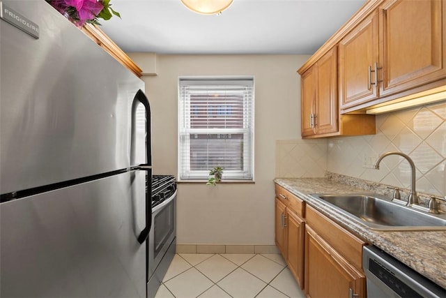 kitchen featuring appliances with stainless steel finishes, a sink, decorative backsplash, light tile patterned floors, and light countertops