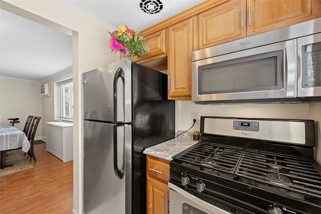 kitchen featuring stainless steel appliances, light wood-style flooring, ornamental molding, a wall unit AC, and light stone counters