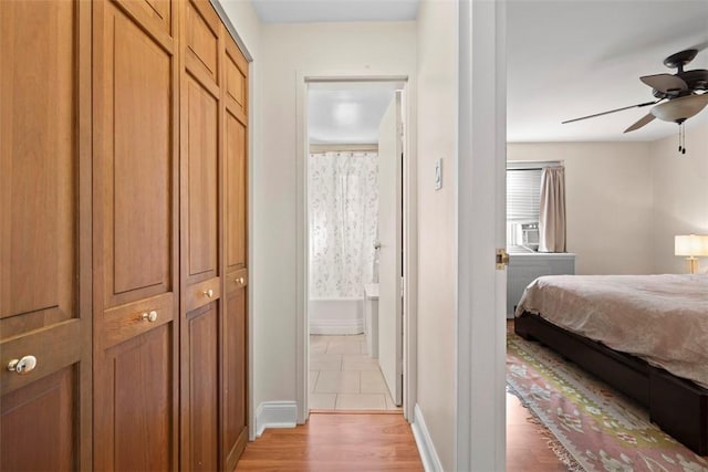 bedroom with radiator heating unit, ensuite bathroom, baseboards, light wood finished floors, and cooling unit