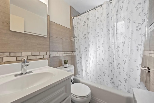 bathroom featuring toilet, tile walls, shower / bath combo with shower curtain, vanity, and decorative backsplash