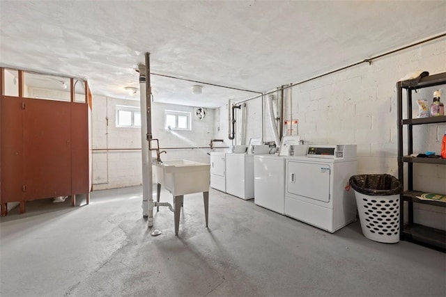 below grade area featuring washing machine and clothes dryer and concrete block wall