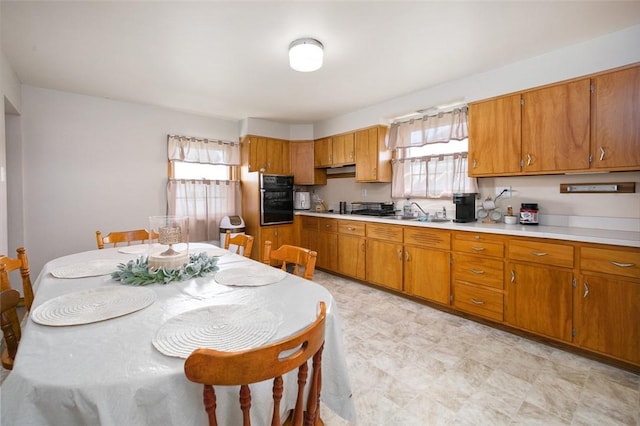 kitchen with oven, brown cabinetry, and light countertops