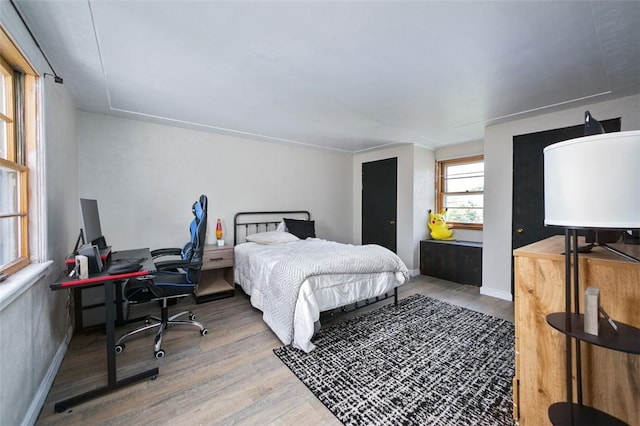 bedroom featuring wood finished floors, an office area, and baseboards