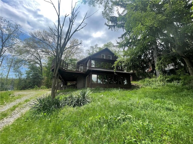 rear view of property featuring a deck and dirt driveway