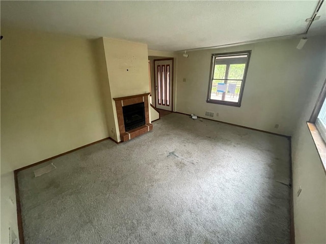 unfurnished living room featuring a brick fireplace, carpet floors, and baseboards