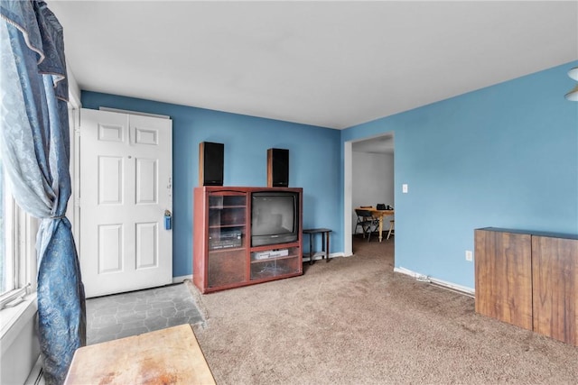 carpeted living area with baseboards and a desk