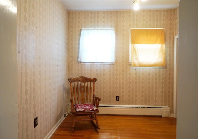 unfurnished room featuring wood finished floors, a baseboard radiator, and wallpapered walls