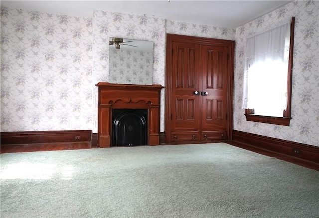 unfurnished living room featuring wallpapered walls, a fireplace, carpet, and baseboards