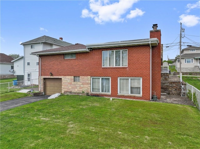 rear view of property featuring a chimney, asphalt driveway, an attached garage, and brick siding