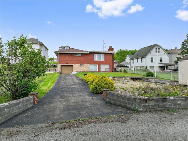 view of front of house with brick siding, a chimney, a garage, fence, and driveway